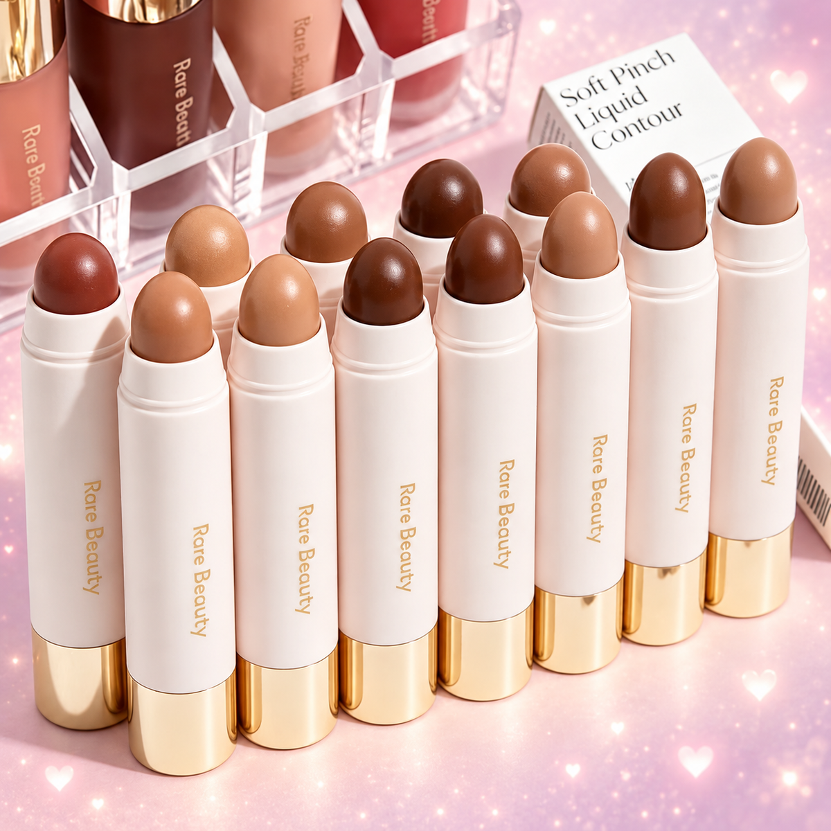 Rare Beauty contour sticks on a blush pink and lavender sparkly background
